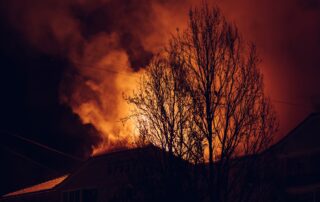 Wildfire flames engulfing a building at night, showing the risks of disasters for emergency preparedness. Use Asthma & Allergy Friendly Certified products