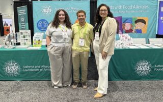 Three members of the Asthma and Allergy Foundation of America team standing in front of the AAFA booth at the AAP 2026 National Conference & Exhibition in San Diego